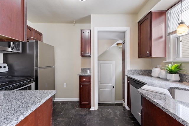 kitchen with baseboards, light stone counters, stainless steel appliances, dark brown cabinets, and pendant lighting