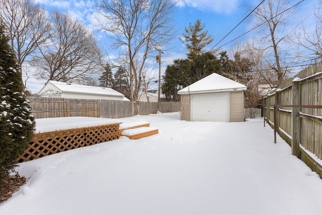 snowy yard featuring a garage, an outdoor structure, and a fenced backyard