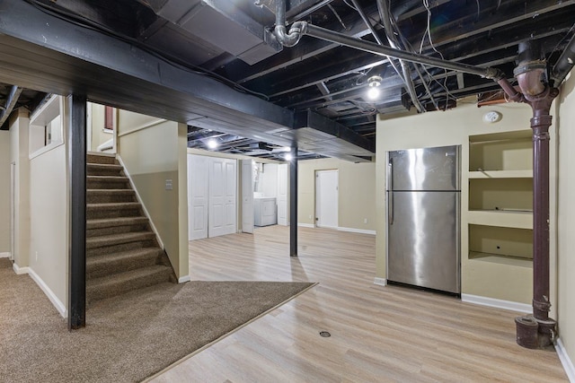 finished basement with wood finished floors, baseboards, stairway, freestanding refrigerator, and washer / clothes dryer