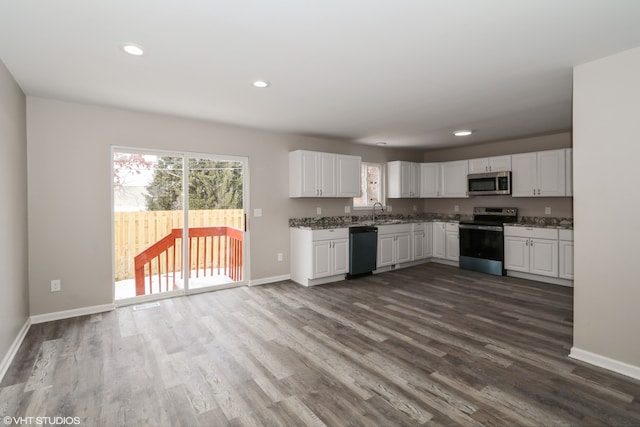 kitchen with stainless steel appliances, white cabinets, dark wood finished floors, and baseboards