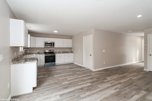 kitchen with stainless steel appliances, light wood-style flooring, white cabinetry, and light stone countertops