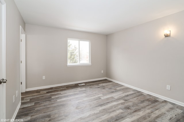 spare room featuring baseboards and wood finished floors