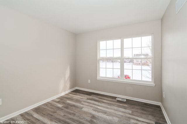 spare room with plenty of natural light, wood finished floors, and visible vents