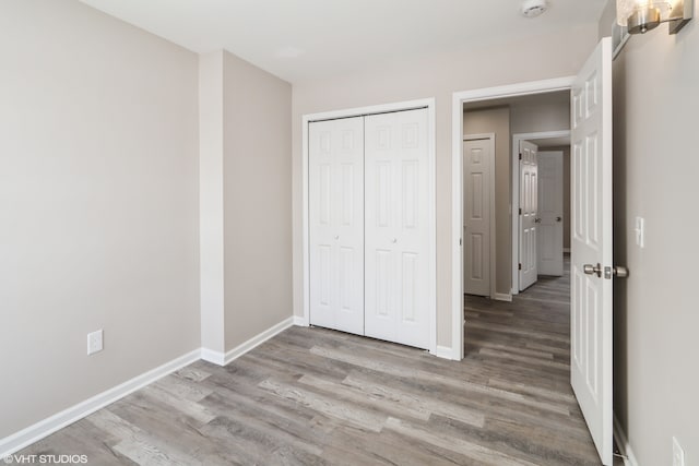 unfurnished bedroom featuring a closet, light wood finished floors, and baseboards