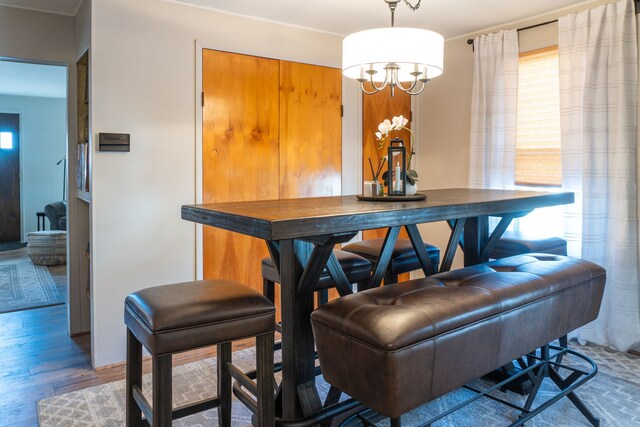 dining space with a dry bar, a chandelier, and wood finished floors