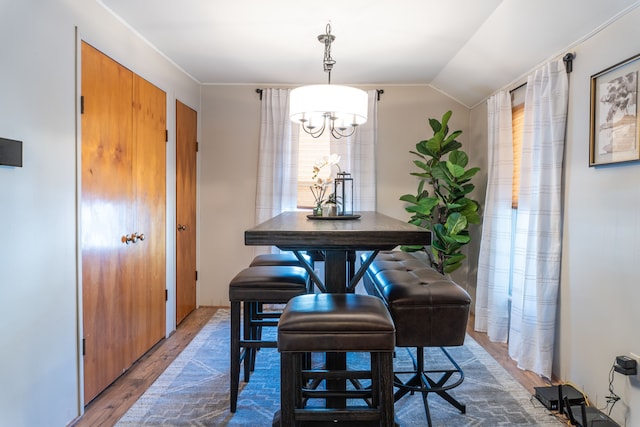 dining room with vaulted ceiling, wood finished floors, and a chandelier