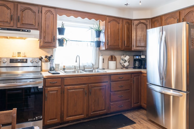 kitchen featuring stainless steel appliances, light countertops, a sink, and under cabinet range hood