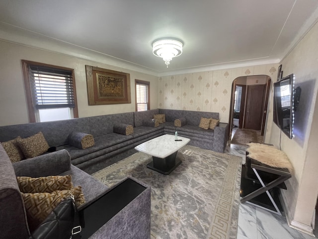 living room with arched walkways, marble finish floor, crown molding, and wallpapered walls