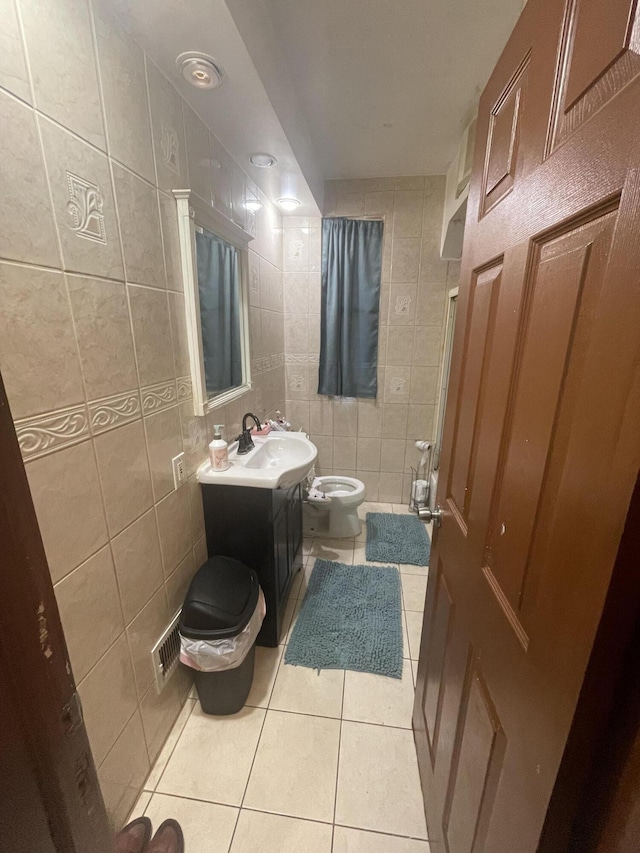 bathroom with tile walls, visible vents, toilet, vanity, and tile patterned flooring