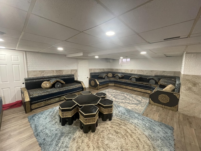 sunken living room featuring wainscoting, wood finished floors, and a paneled ceiling