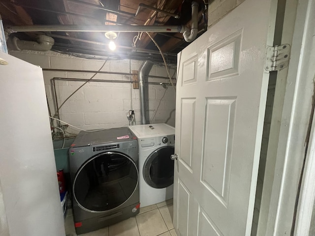 clothes washing area with laundry area, light tile patterned floors, and washing machine and clothes dryer