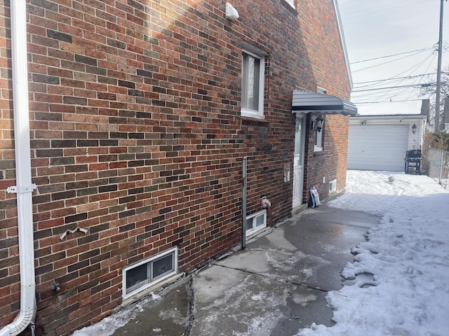 view of snow covered exterior featuring a garage and brick siding