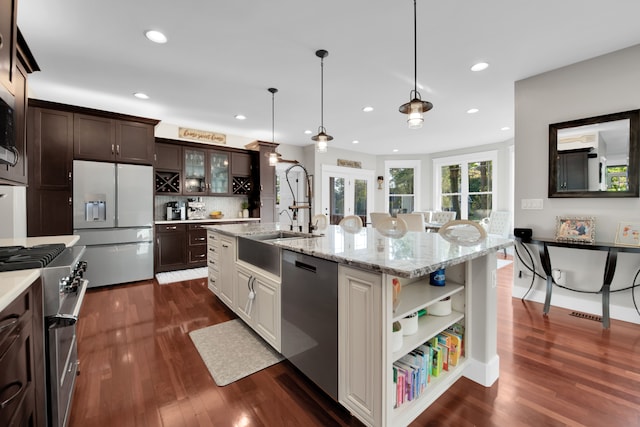 kitchen featuring open shelves, stainless steel appliances, glass insert cabinets, a kitchen island with sink, and white cabinets