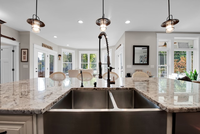 kitchen featuring light stone counters, recessed lighting, open floor plan, hanging light fixtures, and french doors