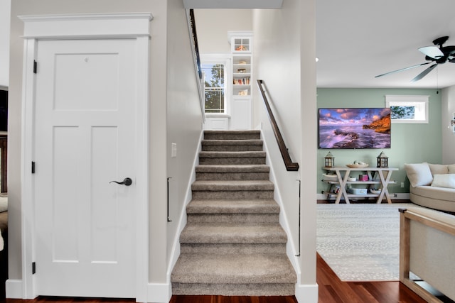 stairs with ceiling fan and baseboards