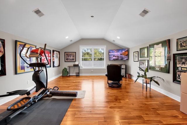 exercise area featuring lofted ceiling, light wood-style flooring, visible vents, and baseboards