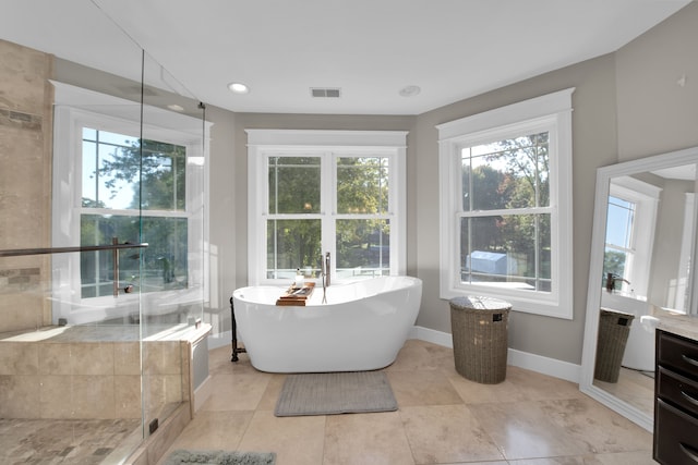 full bath featuring visible vents, baseboards, vanity, a freestanding tub, and a shower stall