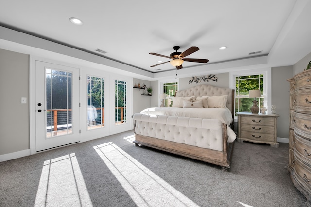 bedroom with access to exterior, a tray ceiling, visible vents, and baseboards