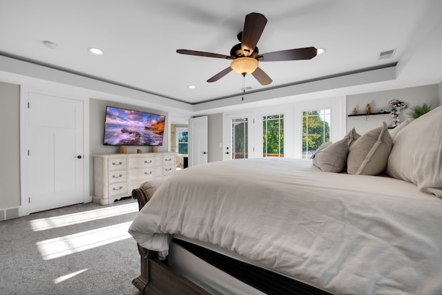 carpeted bedroom featuring visible vents, a raised ceiling, and recessed lighting