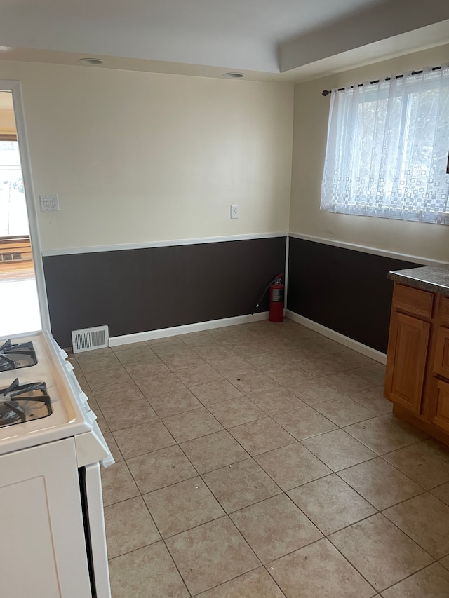 empty room with visible vents, baseboards, and light tile patterned floors