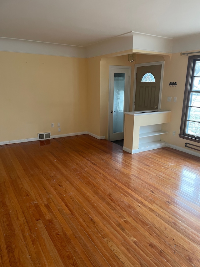 spare room with light wood finished floors, visible vents, and baseboards