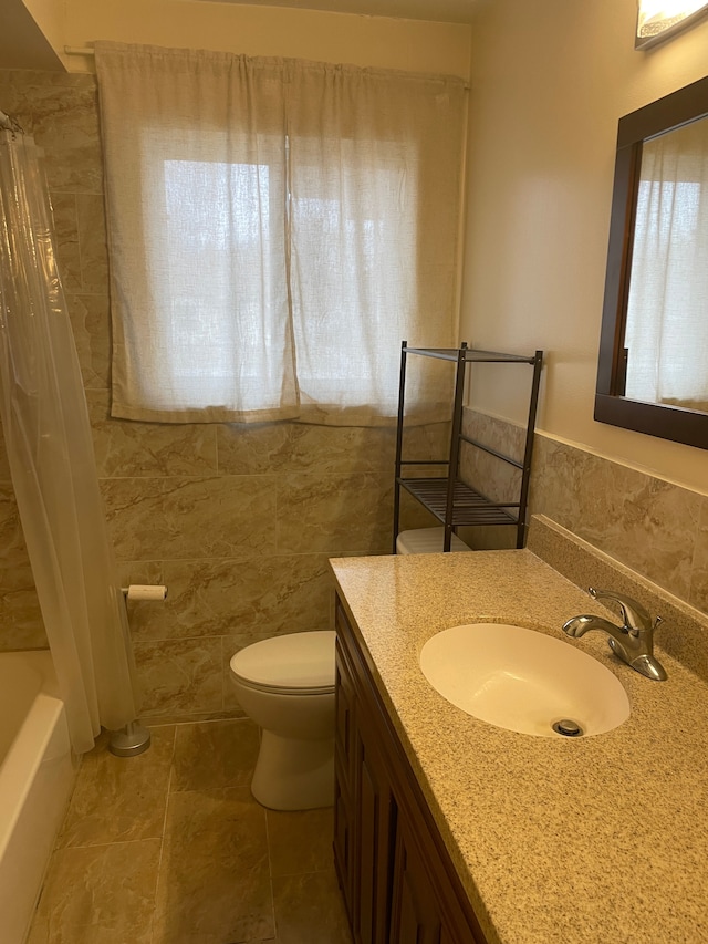 full bath featuring vanity, shower / bath combination with curtain, toilet, and tile walls