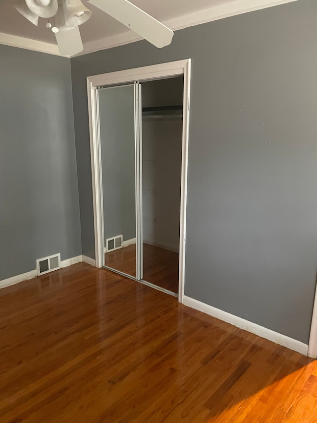 unfurnished bedroom featuring a closet, wood finished floors, visible vents, and baseboards