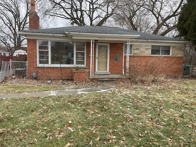 bungalow-style home with brick siding, fence, stone siding, a chimney, and a front yard