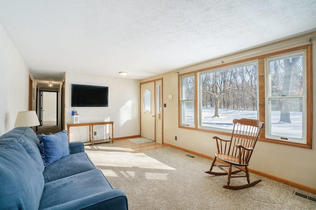 living room featuring light colored carpet, visible vents, a textured ceiling, and baseboards