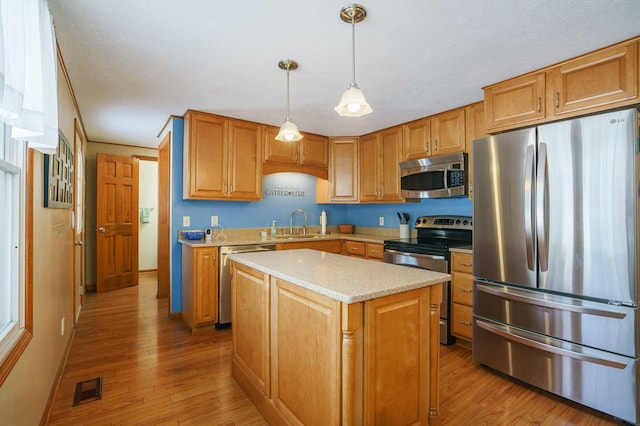 kitchen featuring decorative light fixtures, visible vents, appliances with stainless steel finishes, light wood-style floors, and a kitchen island