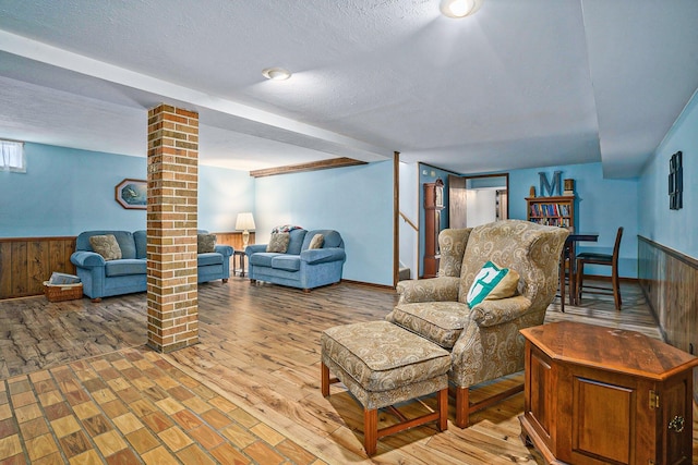 living area featuring a textured ceiling, wood finished floors, and wainscoting