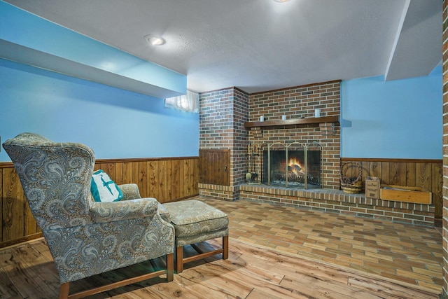 living room with a wainscoted wall, wooden walls, and a fireplace