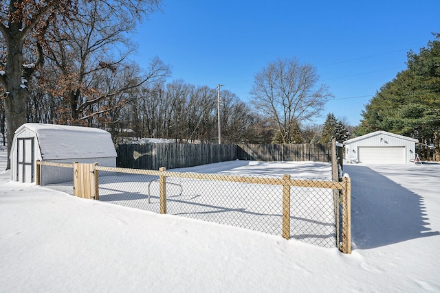 yard layered in snow with a garage, an outdoor structure, and fence