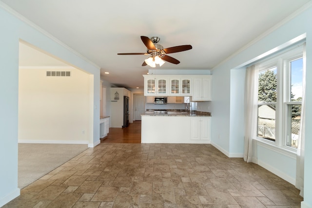 kitchen featuring ornamental molding, freestanding refrigerator, stainless steel microwave, and visible vents