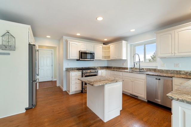 kitchen with dark wood-style floors, light stone countertops, stainless steel appliances, white cabinetry, and a sink