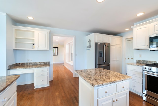 kitchen featuring light stone counters, stainless steel appliances, dark wood-type flooring, white cabinets, and built in desk