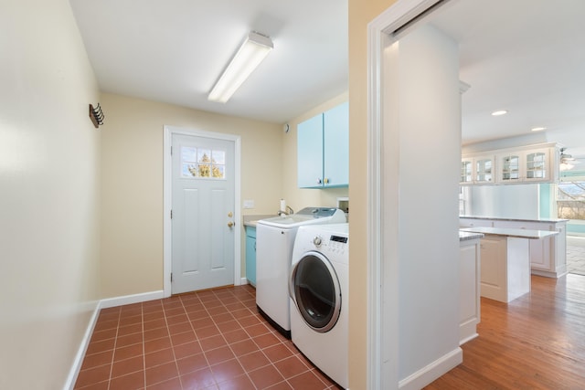 clothes washing area featuring cabinet space, washing machine and dryer, light tile patterned floors, and baseboards