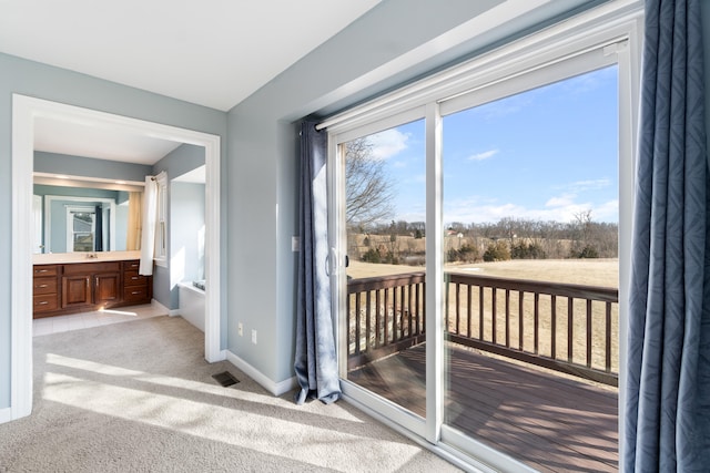 doorway to outside featuring carpet floors, visible vents, and baseboards