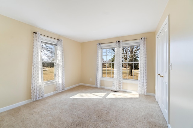 carpeted empty room with plenty of natural light and baseboards