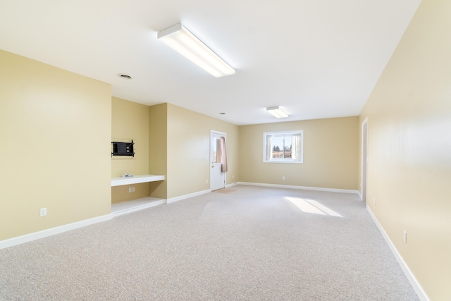 spare room featuring light carpet, visible vents, and baseboards