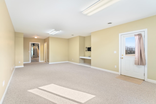 spare room featuring light carpet and baseboards