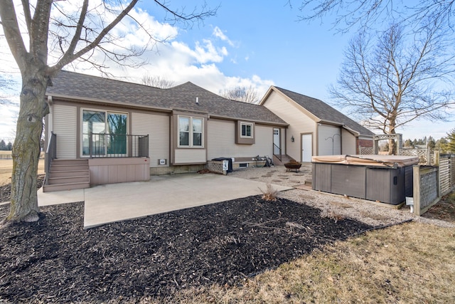 back of house with a patio area, a hot tub, and roof with shingles