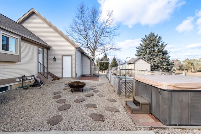 view of yard featuring entry steps, an outdoor fire pit, fence, and a hot tub