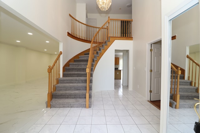 staircase with tile patterned floors, a towering ceiling, and recessed lighting