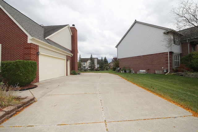 view of side of home featuring brick siding, a chimney, concrete driveway, a lawn, and an attached garage