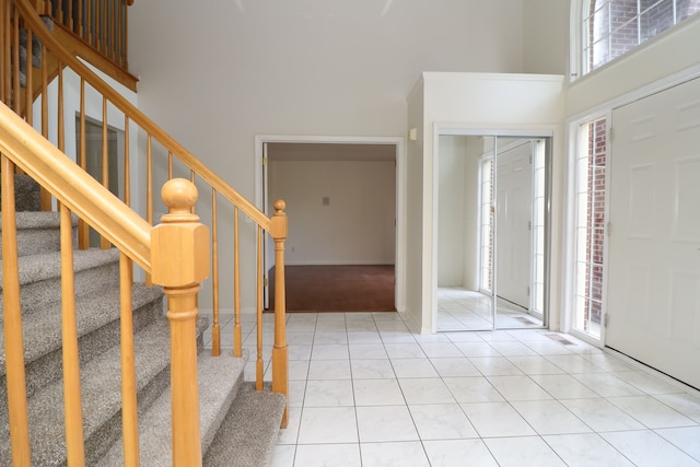 foyer featuring stairs, a high ceiling, and light tile patterned flooring