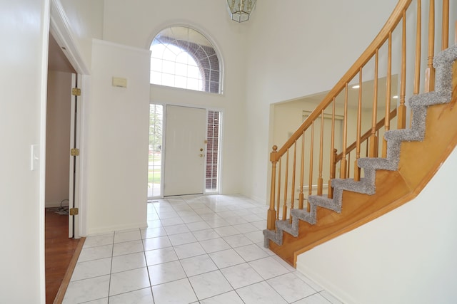 foyer featuring light tile patterned floors, a high ceiling, and stairs