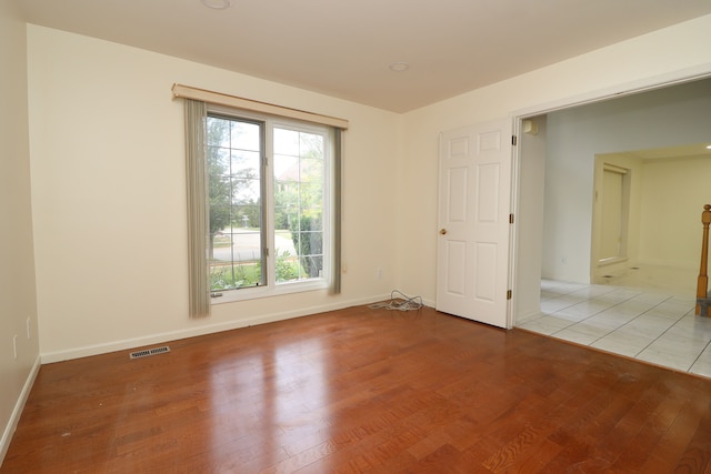 spare room with light wood-style floors, baseboards, and visible vents