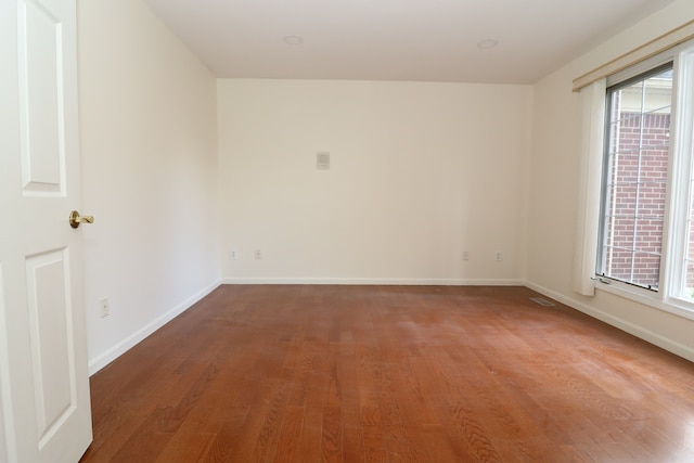 spare room featuring baseboards, wood finished floors, and a healthy amount of sunlight