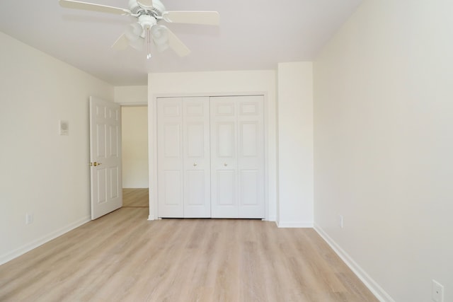 unfurnished bedroom featuring a ceiling fan, light wood-style flooring, baseboards, and a closet